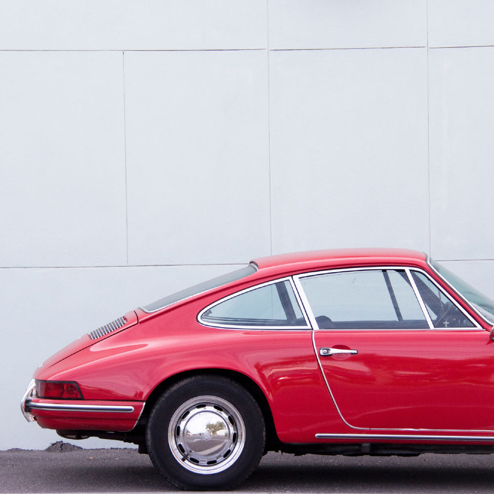 Backend of a parked red sports car funded by specialist car finance against a white background